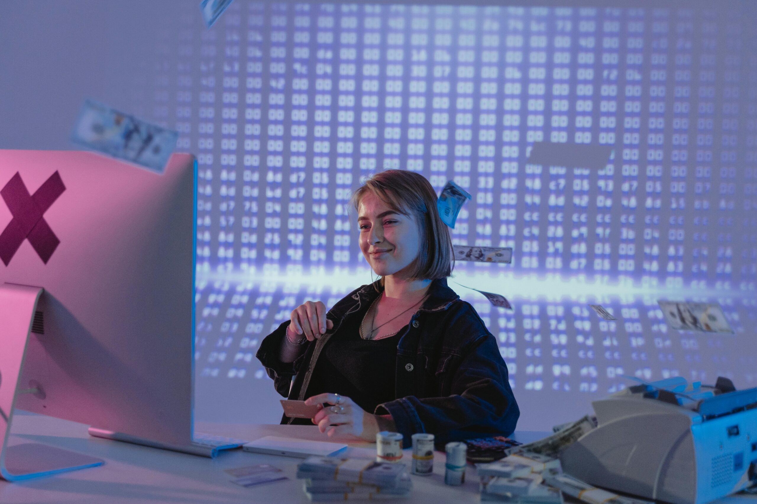 Smiling woman surrounded by digital and physical currency in a tech office setting.
